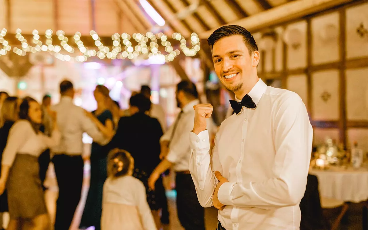 DJ Marcel steht vor den tanzenden Gästen und schaut in die Kamera